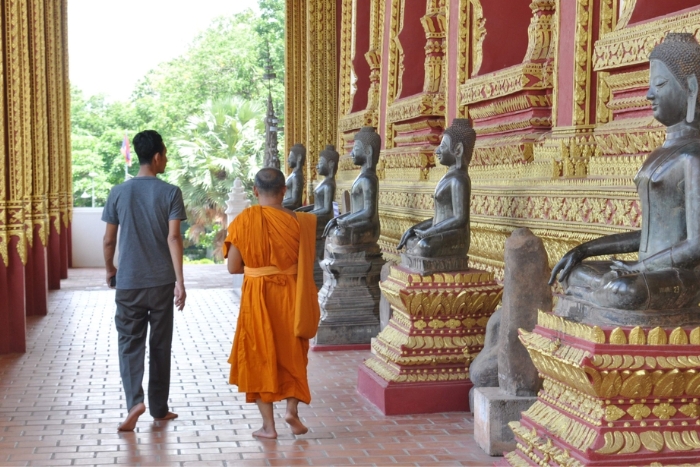 When visiting temples in Laos, dress modestly, stay quiet, remove your shoes, and ask permission before taking photos